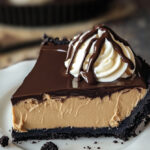 It looks like you've uploaded another image of the Chocolate Peanut Butter Pie! This image again showcases the rich and smooth texture of the pie, with its dark Oreo cookie crust and decadent peanut butter filling, topped with a glossy layer of chocolate ganache and whipped cream. Feel free to share if you need any help with writing a blog post, formatting this recipe, or any other requests!